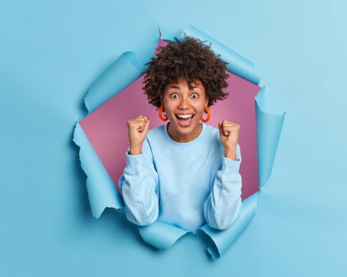 Femme avec un sourire et poings en l'air heureuse d'être en portage salarial chez Coop RH